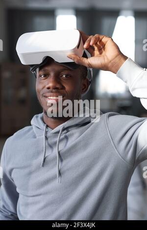 Ritratto di giovane giocatore africano in occhiali di realtà virtuale sorridenti alla telecamera Foto Stock