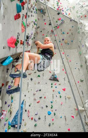 Scalatore femmina durante il suo faticoso allenamento in corrispondenza di una parete di arrampicata indoor hall Foto Stock