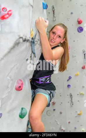 Scalatore femmina durante il suo faticoso allenamento in corrispondenza di una parete di arrampicata indoor hall Foto Stock