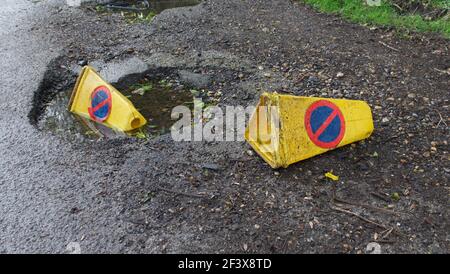 Due coni gialli di segnalazione del traffico scartati gettati su terreno accidentato Foto Stock