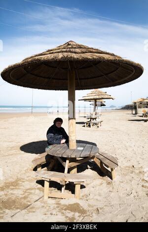 Perranporth, Cornovaglia, 18 marzo 2021, UNA signora si siede ad un tavolo tropicale durante il blocco in Perranporth, Cornovaglia in un giorno di sole. Credit: Keith Larby/Alamy Live News Foto Stock