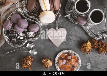 Set di diversi macaron francesi per tè e caffè. Macaron al cioccolato e alla vaniglia con caffè e zucchero al caramello su un tavolo di legno. Vista dall'alto. Foto Stock