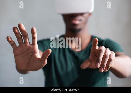 Black man in visore VR che gioca a videogiochi interattivi, esplorando la realtà aumentata Foto Stock