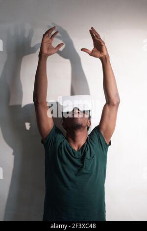 Giovane uomo con occhiali di realtà virtuale che toccano l'aria durante L'esperienza di realtà virtuale a casa tua Foto Stock