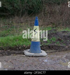 Segnalazione di pericolo dei cavi sospesi sul cono stradale blu e giallo Foto Stock