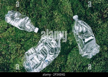 Bottiglie vuote in plastica su fondo di muschio verde. Vista dall'alto, spazio di copia. Zero sprechi. Concetto di inquinamento, protezione dell'ambiente. Riutilizzare i rifiuti Foto Stock