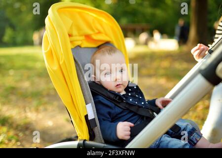 Bambino dolce seduto in un passeggino all'aperto. Bambino piccolo in pRAM. Bambino in passeggino. Passeggiate estive con i bambini. Vacanza in famiglia con bambino piccolo Foto Stock