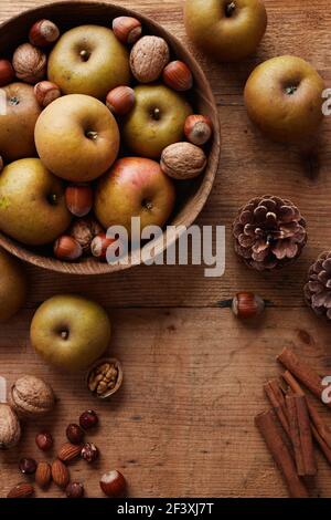 Mele autunnali con noci e bastoni di cannella sul tavolo, vista dall'alto. Heirloom reinette mele. Foto Stock