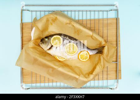 Piatto al forno o alla griglia di pesce dorado con limone cotto home su sfondo blu Foto Stock