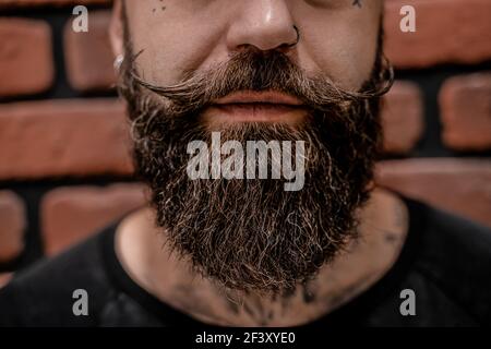 Primo piano di bello hipster vecchio-fashioned tatooed e trafitto su uno sfondo di mattone. Foto Stock