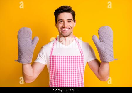 Ritratto fotografico di un ragazzo che mostra due mani in guanti da cucina isolato su sfondo giallo brillante Foto Stock