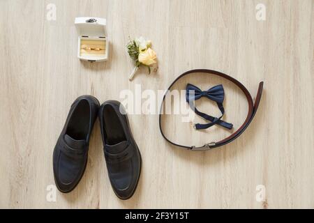 Set di accessori per lo sposo con disposizione piatta su pavimento in legno. Concetto di moda per matrimoni. Foto Stock