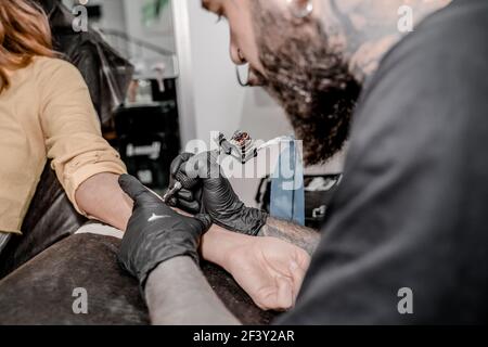 Primo piano della macchina per tatuaggio. Tatuaggio. Uomo che crea una foto sulla sua mano da un artista professionista tatuaggio Foto Stock
