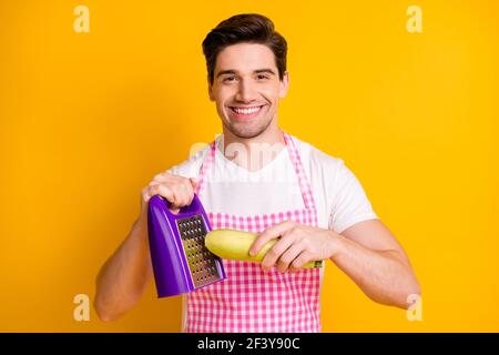 Ritratto fotografico di un uomo sorridente che grattugiava squash isolato su vivido sfondo giallo Foto Stock