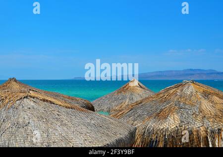 Paesaggio con ombrelli palapa e vista panoramica di Playa El Tecolote, una spiaggia isolata di sabbia bianca con acque turchesi a la Paz, Messico. Foto Stock