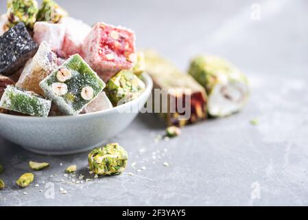 Baklava, halva, rahat lokum, sherbet, noci, pistacchi, in ciotola su fondo grigio. Dolci orientali tradizionali assortiti, dolci arabi, turchi Foto Stock