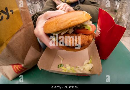 New York, Stati Uniti. 17 Marzo 2021. Un ristoratore si prepara a pranzo su un McDonald's Crispy Chicken Sandwich Deluxe mentre cena all'aperto a New York mercoledì 17 marzo 2021. Nel 2019 Popeye's ha debuttato il suo sandwich di pollo con grande successo, portando quasi ogni catena di fast food a generare un piatto di pollo croccante. McDonald's è finalmente entrato come il 800-lb gorilla e ha già portato ad una spinta di traffico piede nei suoi ristoranti. (ÂPhoto di Richard B. Levine) Credit: Sipa USA/Alamy Live News Foto Stock