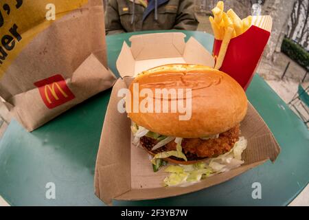 New York, Stati Uniti. 17 Marzo 2021. Un ristoratore si prepara a pranzo su un McDonald's Crispy Chicken Sandwich Deluxe mentre cena all'aperto a New York mercoledì 17 marzo 2021. Nel 2019 Popeye's ha debuttato il suo sandwich di pollo con grande successo, portando quasi ogni catena di fast food a generare un piatto di pollo croccante. McDonald's è finalmente entrato come il 800-lb gorilla e ha già portato ad una spinta di traffico piede nei suoi ristoranti. (Foto di Richard B. Levine) Credit: Sipa USA/Alamy Live News Foto Stock