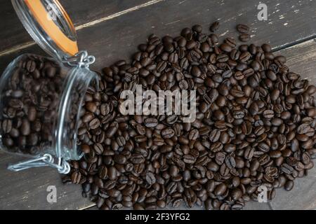 Vista dall'alto, chicchi di caffè tostati in vasetto di vetro in stile rustico sfondo di legno Foto Stock