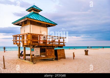 Sunny Isles Beach, Stati Uniti d'America - 7 maggio 2018: Bagnino edificio lungo la costa dell'oceano a Miami, Florida tramonto serale con persone che camminano sulla sabbia Foto Stock