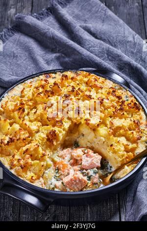 torta al salmone con eglefino affumicato, gamberi, spinaci, condita con purè di patate in un piatto da forno, cucina inglese Foto Stock