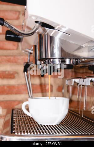 Macchina per caffè espresso italiana al banco del ristorante che offre caffè appena fatto caffè in una piccola tazza Foto Stock