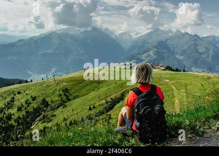 Bionda ragazza godendo di vista durante il trekking nelle Alpi, Austria.Majestic cime di montagne, prati verdi, vista della valle. Attivo Happy Backpacker.Travel Foto Stock