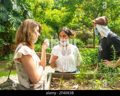 Medellin, Antioquia, Colombia - 6 gennaio 2021: Donna Latina con una maschera sotto la bocca nel mezzo di una donna e uomo caucasici Foto Stock