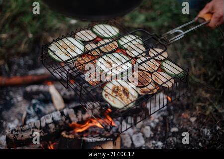 Accoppia in un plaid a scacchi arrostendo marshmallows sul fuoco vicino alla casa del rimorchio. Foto Stock