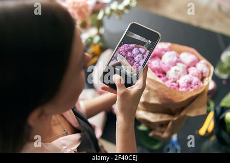 Primo piano foto fiorista al lavoro. Donna che fa foto di decorazioni floreali primaverili. Foto Stock