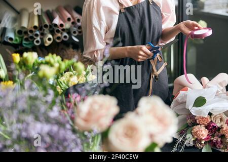 Primo piano foto fiorista al lavoro. Donna che fa le decorazioni floreali primaverili. Foto Stock