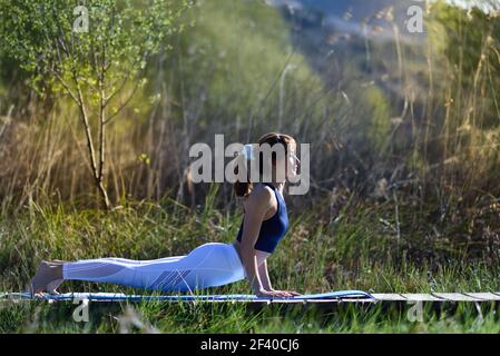 Giovane donna fare yoga in natura. Femmina di indossare abbigliamento sportivo. Foto Stock