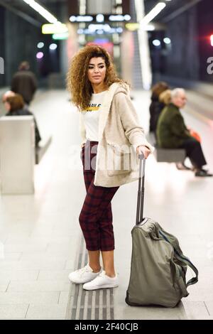 Bellissima giovane turista arabo in attesa il suo treno in una stazione della metropolitana. Ragazza araba in abiti casual. Foto Stock