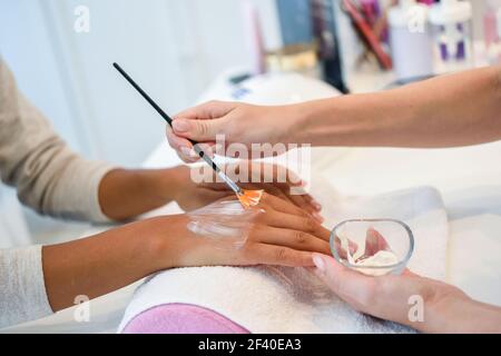 Primo piano di estetista che applica la crema sulla mano di woman&rsquo;s usando il pennello. Cura delle mani, cura delle mani, concetto cosmetico. Foto Stock