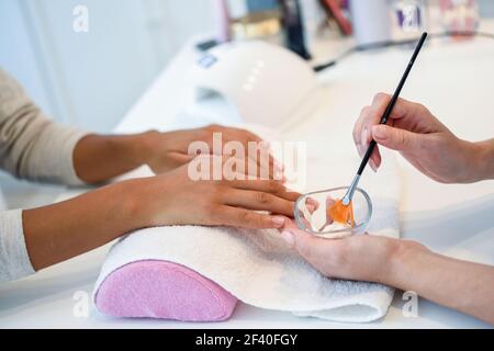 Primo piano di estetista che applica la crema sulla mano di woman&rsquo;s usando il pennello. Cura delle mani, cura delle mani, concetto cosmetico. Foto Stock