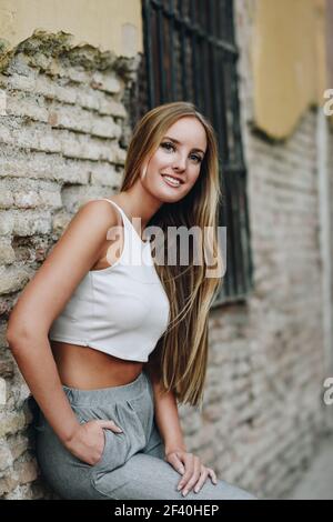 Bionda ragazza che indossa abiti casual per strada. Giovane donna in ambiente urbano.. Bionda ragazza che indossa abiti casual per strada. Foto Stock