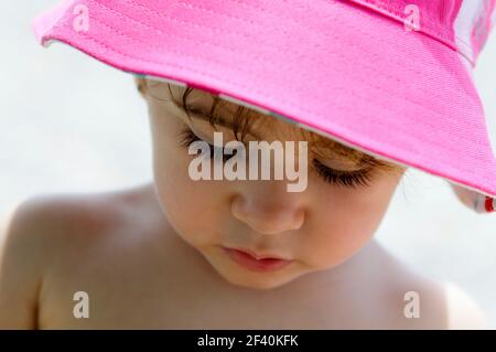 Primo piano di adorabile bambina all'aperto con cappello da sole. Primo piano di adorabile bambina che indossa cappello da sole Foto Stock