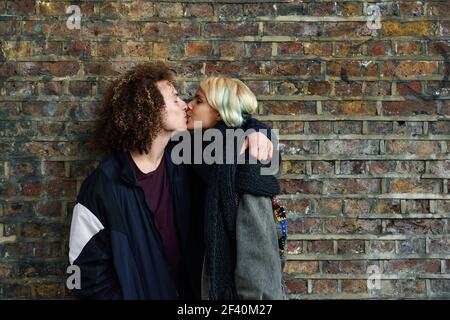 Giovane coppia che si gode Camden città di fronte a un muro di mattoni tipico di Londra, Regno Unito. Uomo e donna che baciano. Giovane coppia che si gode Camden città di fronte a un muro di mattoni tipico di Londra Foto Stock