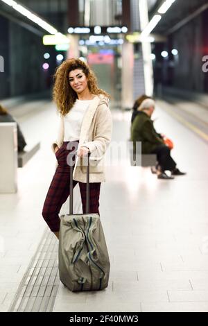 Bella giovane donna arabica in attesa del suo treno in una stazione della metropolitana. Viaggiatore arabo in abiti informali. Giovane donna arabica in attesa del suo treno in una stazione della metropolitana. Foto Stock