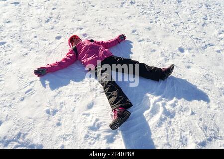 Bambina che fa un angelo di neve che indossa abiti da neve in Sierra Nevada. Bambina che fa un angelo di neve che indossa abiti da neve Foto Stock