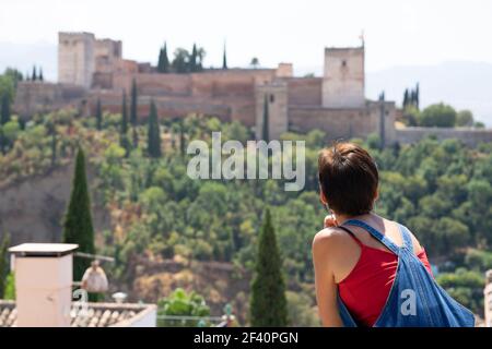 Vista posteriore della donna guardando l'Alhambra di Granada dal punto di vista di San Nicolas. Vista posteriore della donna che guarda l'Alhambra di Granada. Foto Stock