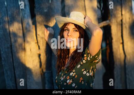 Bella ragazza escursionista, indossando camicia fiorita, che si pone come un modello di moda in campagna. Escursionista giovane donna trekking in campagna al tramonto Foto Stock