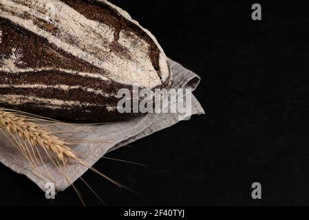 Crosta artigianale di pane di segale scuro su tovagliolo di lino grigio. Spazio di copia. Tasto basso Foto Stock