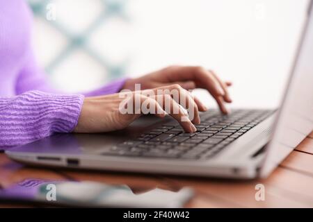 Donna persiana seduta in una poltrona sul suo balcone utilizzando un computer portatile. Donna persiana sul suo balcone utilizzando un computer portatile Foto Stock