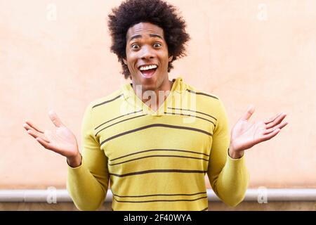 Uomo nero con capelli afro che mette un'espressione divertente all'aperto. Uomo nero con capelli afro che mette un'espressione divertente Foto Stock