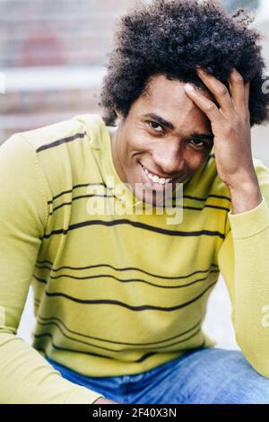 Turista nero cubano con i capelli afro seduti sul pavimento sorridendo alla macchina fotografica. Turista nero cubano con i capelli afro seduti sul pavimento Foto Stock