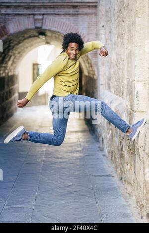 Uomo nero con capelli afro che saltano per la gioia per la strada. Uomo nero con capelli afro che saltano per gioia Foto Stock