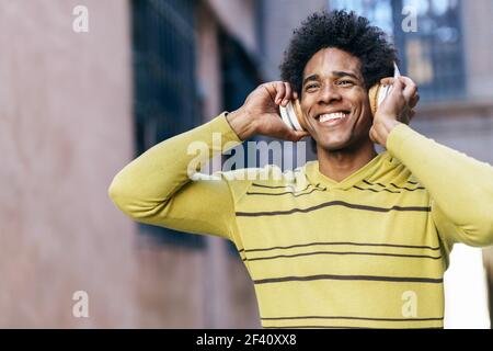 Uomo nero con capelli afro ascolto di musica con cuffie wireless visite turistiche a Granada, Andalusia, Spagna.. Uomo nero che ascolta la musica con le cuffie wireless per visitare Granada Foto Stock