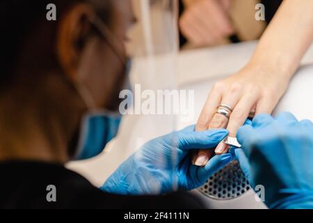 Estetista che fa la manicure, limando le unghie con una lima al suo cliente in un centro di bellezza. Concetti di affari e bellezza. Estetista che fa la manicure, limando le unghie con una lima al suo cliente in un centro di bellezza Foto Stock