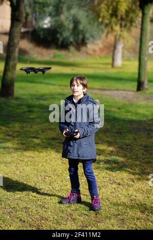 Bambina di nove anni che aziona il drone giocattolo che vola o che si sorvola con il telecomando in un parco. Bambina di nove anni che aziona il drone giocattolo che vola con il telecomando